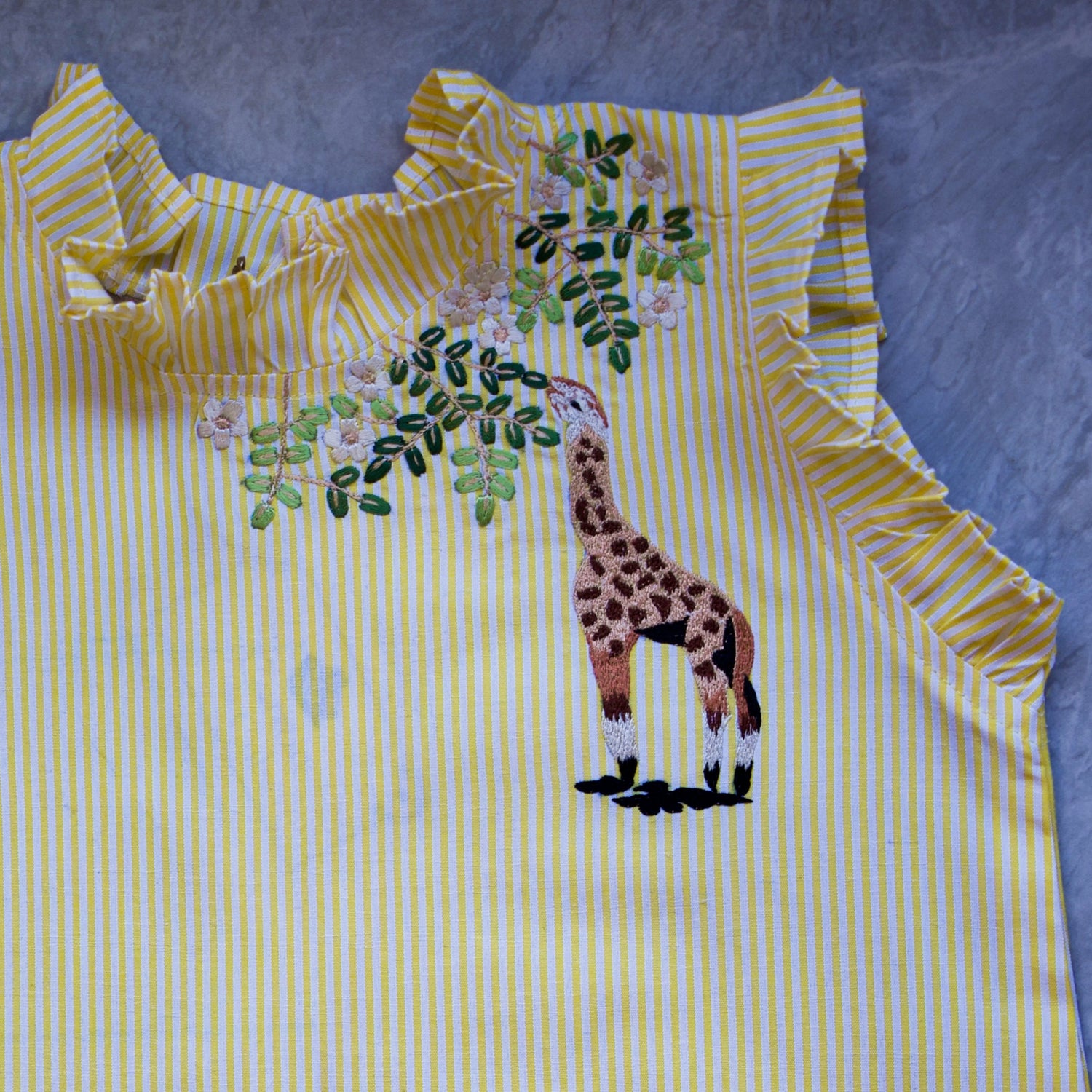 Yellow and white striped shirt with a giraffe design on a blue background